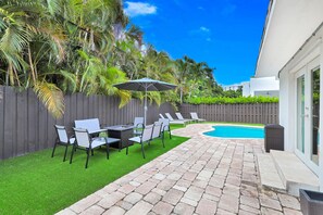 A backyard with a swimming pool, patio furniture, and a wooden fence. - Family-Friendly Beach House, Steps to Beach (Fort Lauderdale)
