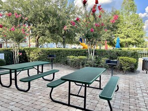 Relax in a serene outdoor space with picnic tables and benches amidst lush greenery and vibrant flowers.