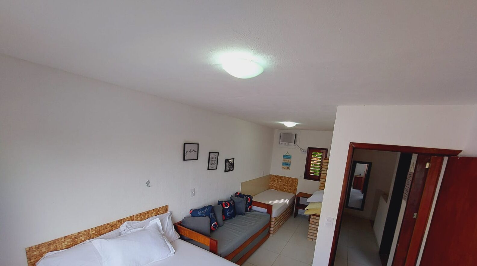 Habitación de hotel compacta con cama, sofá, kitchenette pequeño y baño visible a través de una puerta abierta.