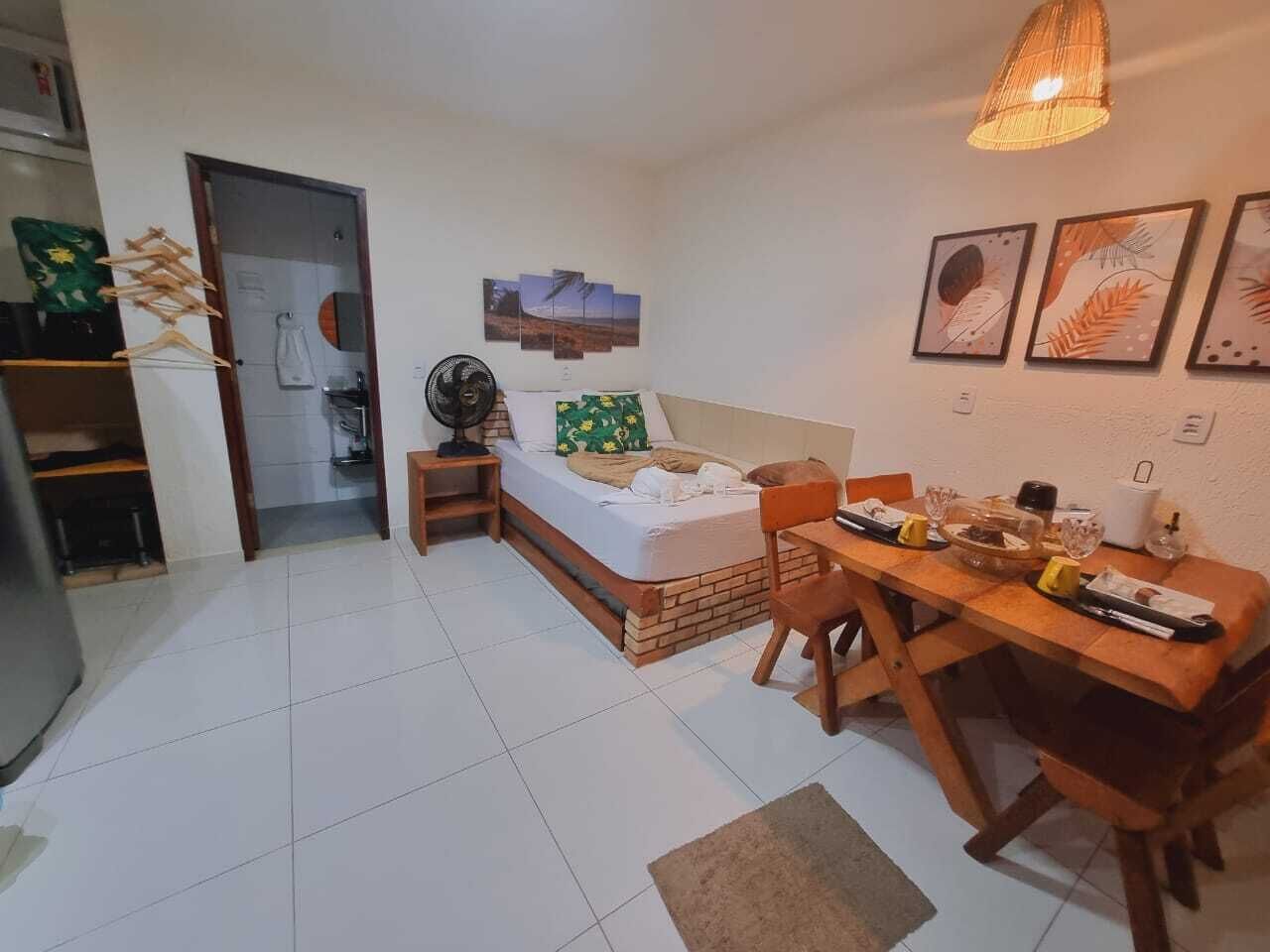Una habitación pequeña con cama, mesa de comedor y una kitchenette.