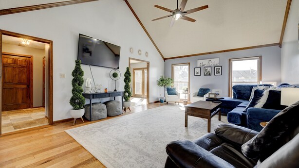 A spacious living room with a wooden floor, a large ceiling fan, a flat-screen TV, and a blue sofa. - Kentucky holiday home with Hot Tub & pool In Louisville KY (Louisville)