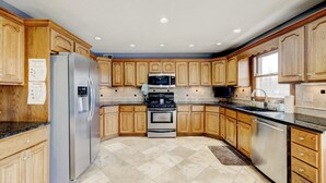 A kitchen with wooden cabinets, stainless steel appliances, and a tiled floor. - Kentucky holiday home with Hot Tub & pool In Louisville KY (Louisville)