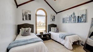 A bedroom with two beds, a wooden headboard, a small table, and a mirror. There are paintings on the walls and a window with a view of the outside. - Kentucky holiday home with Hot Tub & pool In Louisville KY (Louisville)