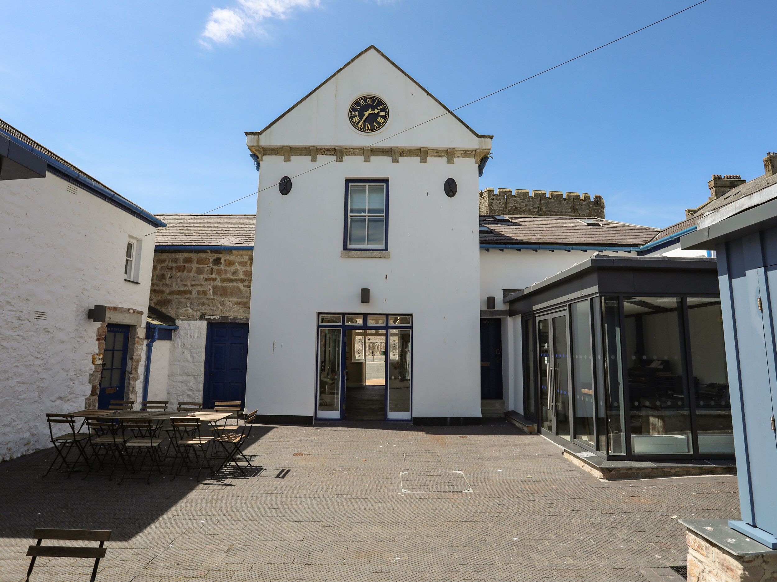 A white building with a clock on the facade, a door, and a small window.