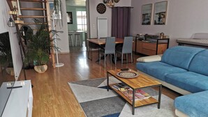 A modern living room with a blue sofa, wooden coffee table, and a dining area with a kitchen in the background. - Maison Dans Charmante Bourgade (Paimbœuf)