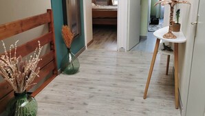 A hallway with a wooden bench, a vase with dried plants, and a small table with a plant. - Maison Dans Charmante Bourgade (Paimbœuf)