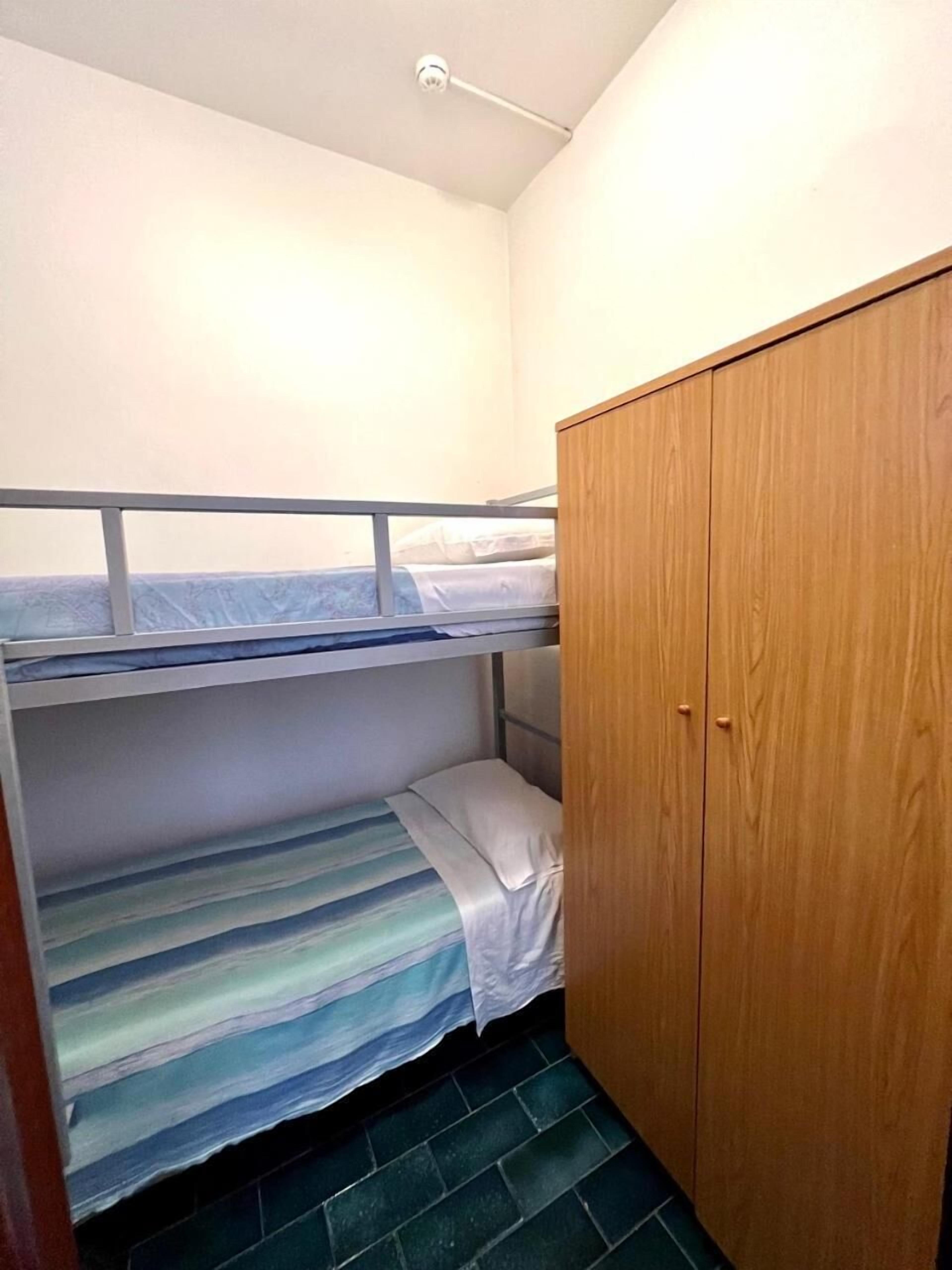 A bunk bed room with a wooden wardrobe and a ceiling light.