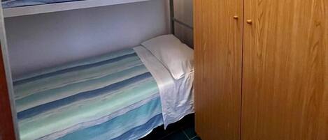 A bunk bed room with a wooden wardrobe and a ceiling light.