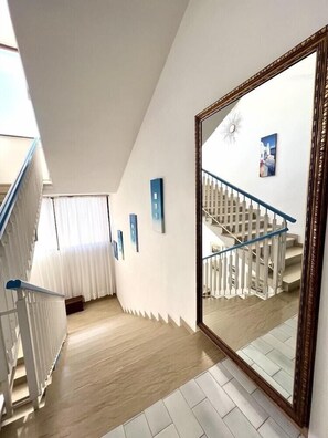 A hallway with a staircase, white walls, and a large mirror reflecting the staircase. - Hotel Giorgetti Palace (Bellaria)