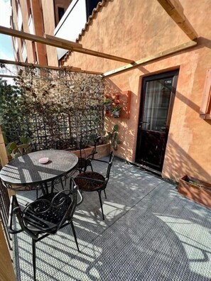 A covered patio with a round table and chairs, a metal fence, and potted plants. - Hotel Giorgetti Palace (Bellaria)
