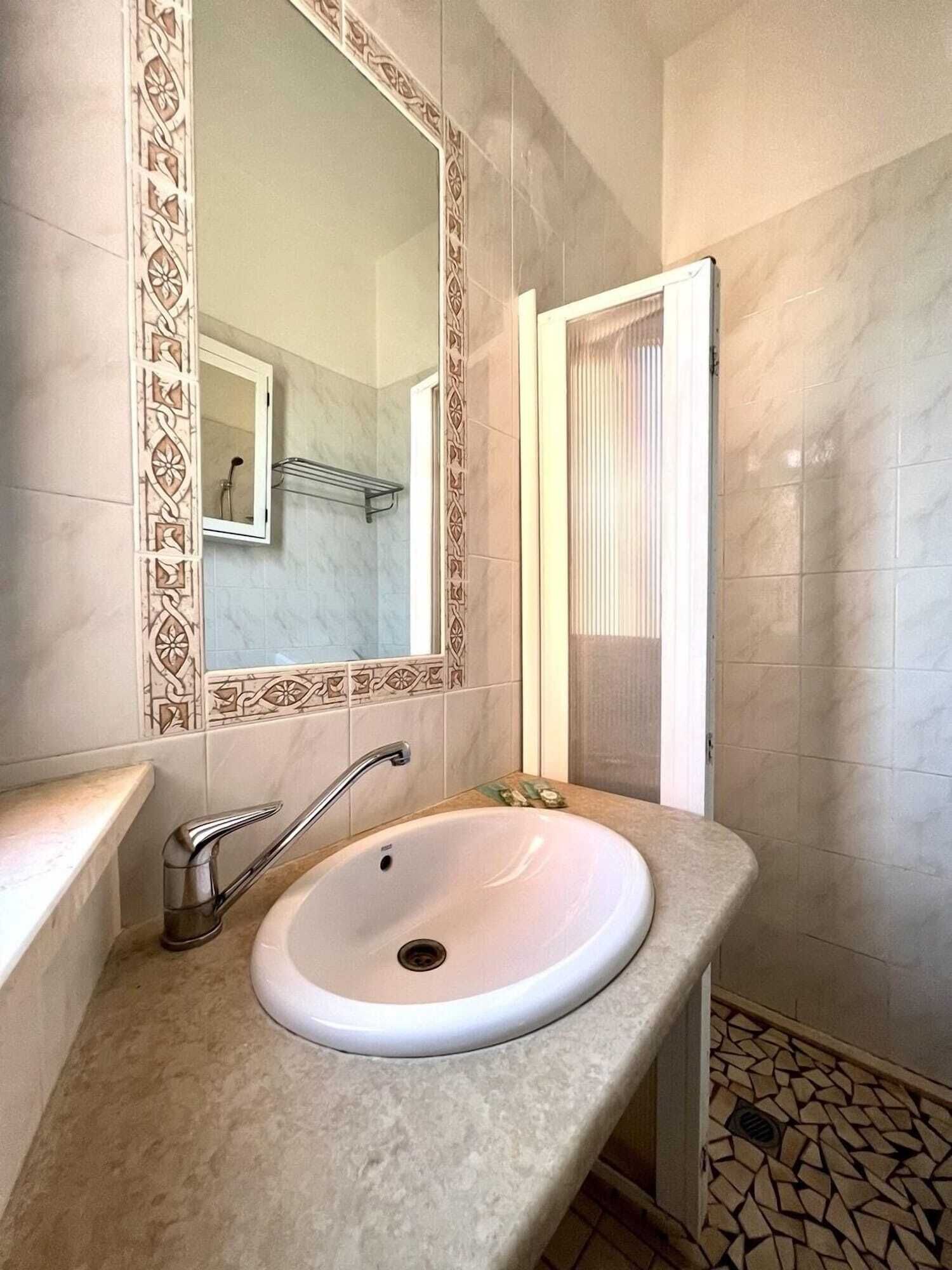 Un baño con lavamanos blanco, un espejo y una puerta de ducha.