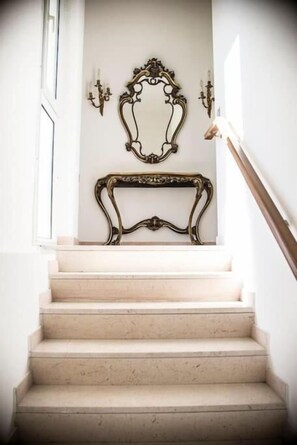 A staircase with a light-colored wall, a decorative mirror, and wall sconces. - Hotel Giorgetti Palace (Bellaria)