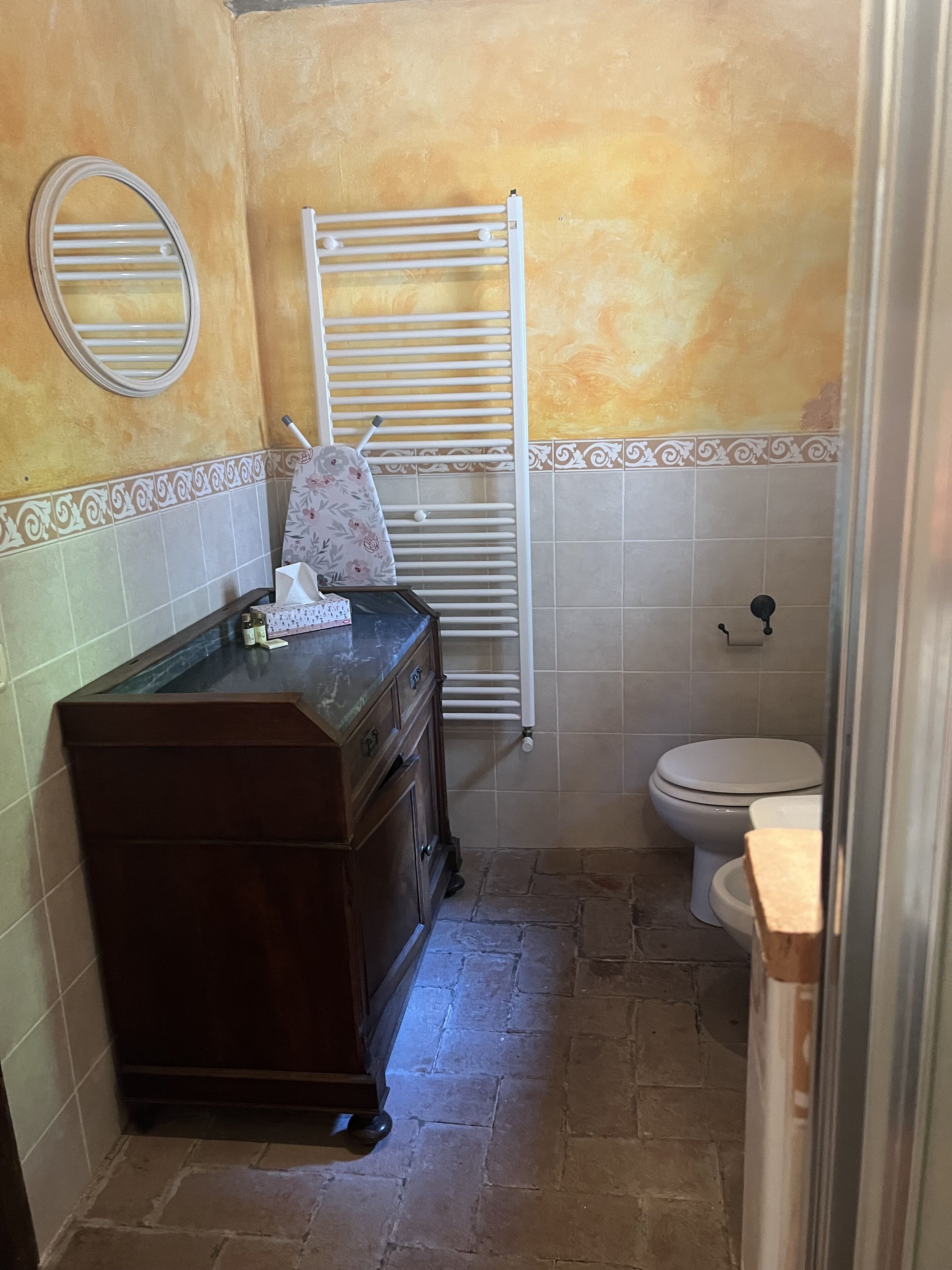 A bathroom with a wooden vanity, a white toilet, and a towel rack.