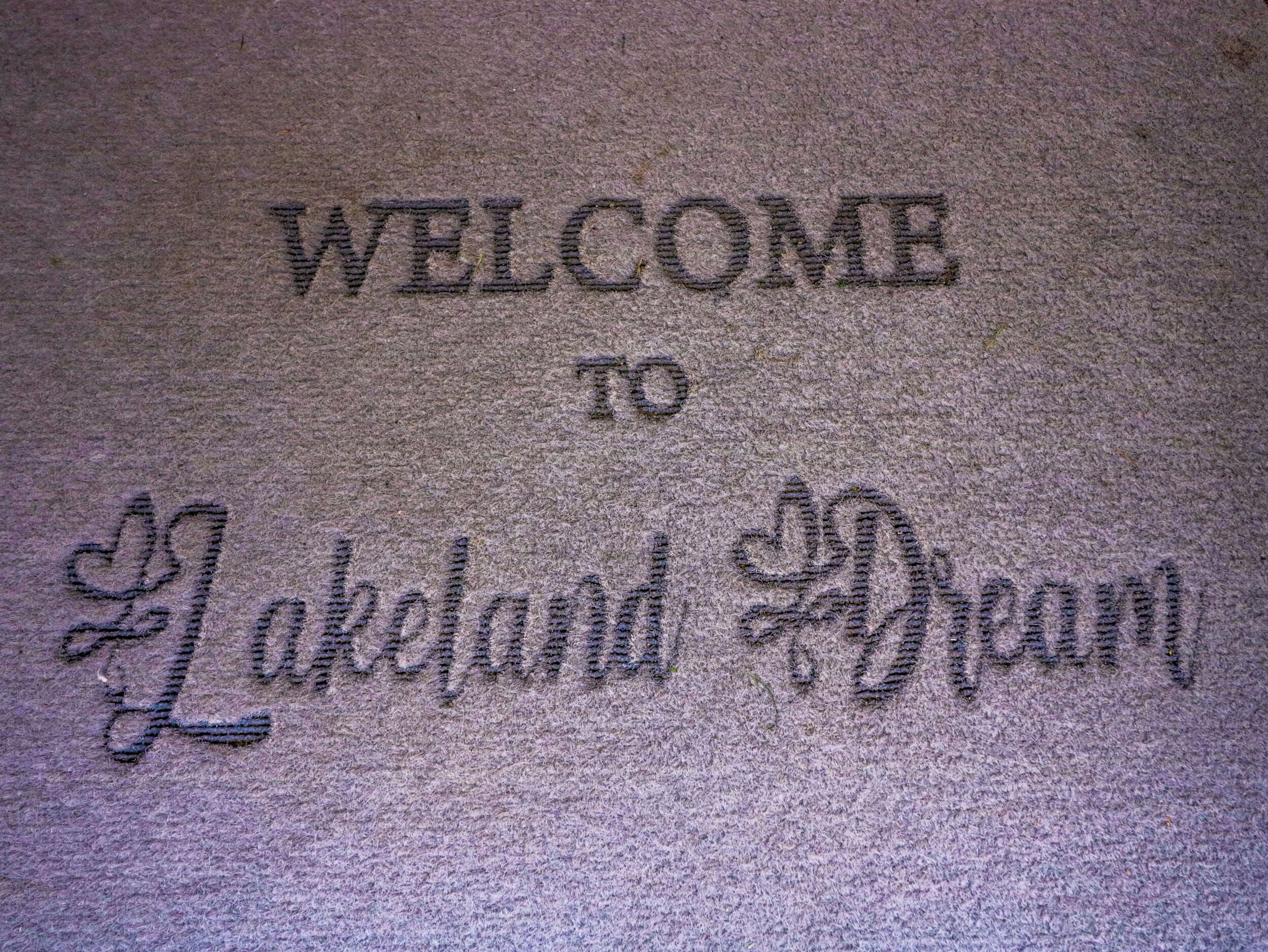 Una felpudo con la inscripción 'WELCOME TO Lakeland Dream'.