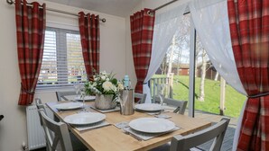 A dining table set for four with a flower centerpiece, white plates, and silverware. - Lakeland Dream @ South Lakeland Leisure Lodge (Carnforth)