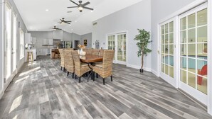 A spacious kitchen with modern appliances, a dining area with wicker chairs, and a view of a swimming pool through glass doors. - 4BR, 4BA, Amazing Indoor Pool, EV charger, ~10 acres retreat, next to Park (Big Pool)