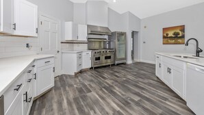 A modern kitchen with white cabinetry, a stainless steel range hood, a built-in oven, and a large island with a sink. - 4BR, 4BA, Amazing Indoor Pool, EV charger, ~10 acres retreat, next to Park (Big Pool)