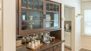 A kitchen with a built-in coffee station, cabinets, and a countertop with various kitchen items.