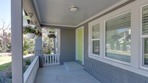 A covered porch with a white railing, a green door, and hanging flower baskets.