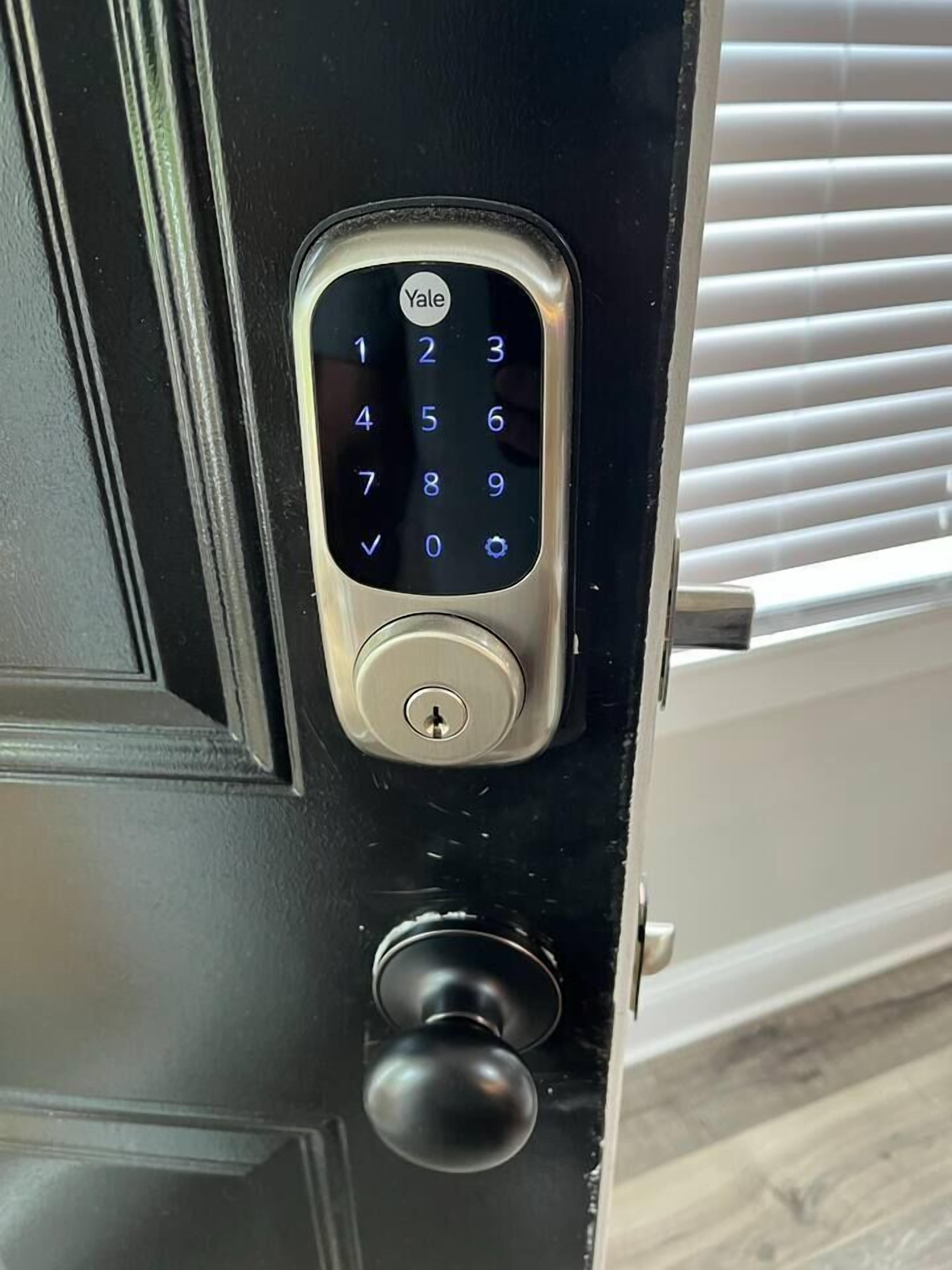 Un cerrojo Yale en una puerta negra con una cerradura debajo.