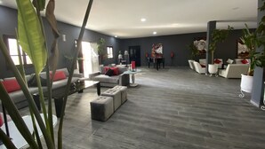 A spacious living area with grey sofas, a coffee table, and potted plants.