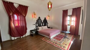 A bedroom with a bed, a nightstand, a decorative wall lamp, and a patterned rug.