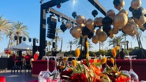 An outdoor event with a stage, red seating, and decorative elements like flowers and lanterns.