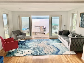 Relax on the deck with serene views of the water, featuring a wooden bench and small table.