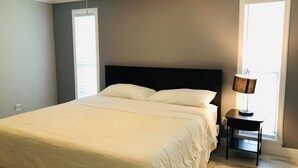 Un dormitori amb un llit, un ventilador de sostre i una tauleta de nit amb una làmpada.