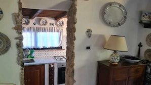 A rustic kitchen with a stone archway leading to a window, a stove, cabinets, and a tiled floor. - Wonderful Villa with garden in Ansedonia (Ansedonia)
