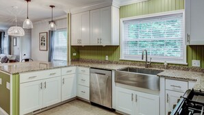 A kitchen with white cabinets, a stainless steel sink, and a dishwasher. - Deacon Stays: The Idlewilde - Walk to WFU (Winston-Salem)