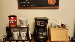 Un coin café avec un tableau noir affichant le menu, proposant différents types de café, des infusions, du thé Earl Grey et du thé vert.