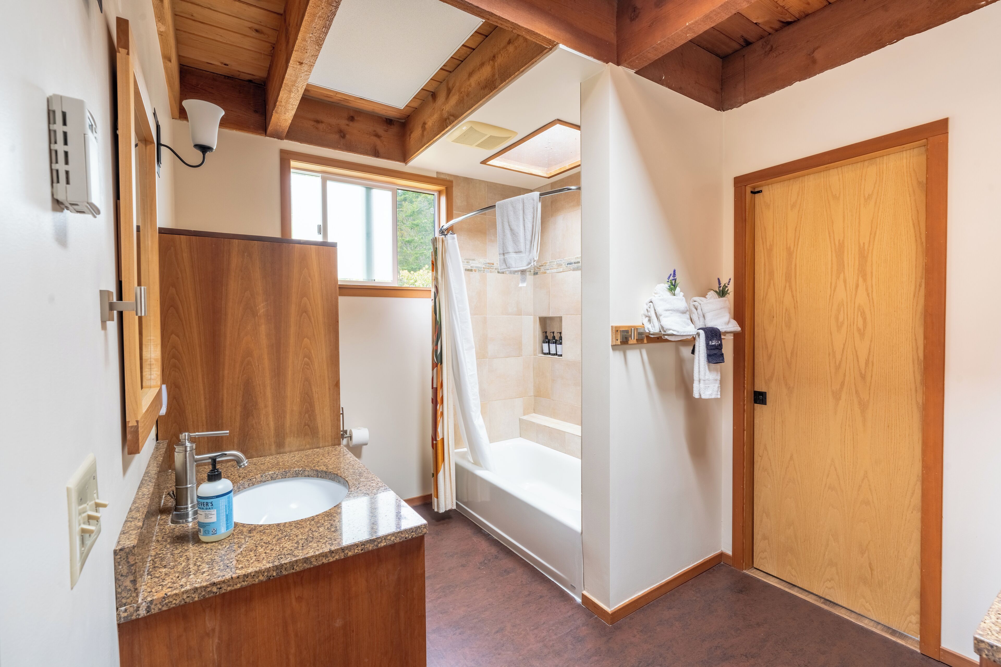 A bathroom with a wooden vanity, a sink, and a shower area.
