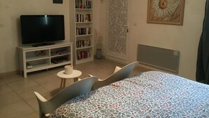 A bedroom with a bed, a TV, a bookshelf, and a door with a decorative panel. - Room with private exit to small garden (Moussac)