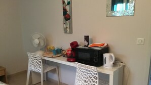 A small kitchenette with a microwave, kettle, and a fan. There are two white chairs and a table with various items on it. - Room with private exit to small garden (Moussac)