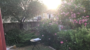 A garden with a table and chairs, surrounded by greenery and flowering plants. - Room with private exit to small garden (Moussac)