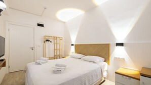 A modern bedroom with a large bed, bedside tables, a wardrobe, and a television. - Casa Gaia Otel (Bozcaada)