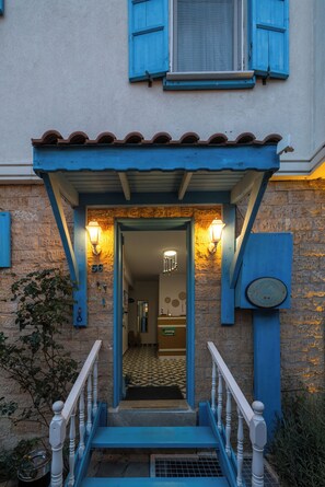 A building entrance with a blue facade, a tiled roof, and a staircase leading to the door. - Casa Gaia Otel (Bozcaada)