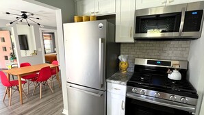 A modern kitchen with stainless steel appliances, a dining area with red chairs, and a brick backsplash. - Near DT Madison - One Block from Lake Monona & Lake Loop Bike Path (Monona)