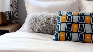 A bedroom with a bed, a window with blinds, patterned curtains, and a lamp on a bedside table. - Near DT Madison - One Block from Lake Monona & Lake Loop Bike Path (Monona)
