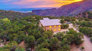 A house surrounded by dense greenery and mountains, with a clear view of the ocean in the background. - Architectural Peace and Perfection in the Sandia Mountains (Albuquerque)