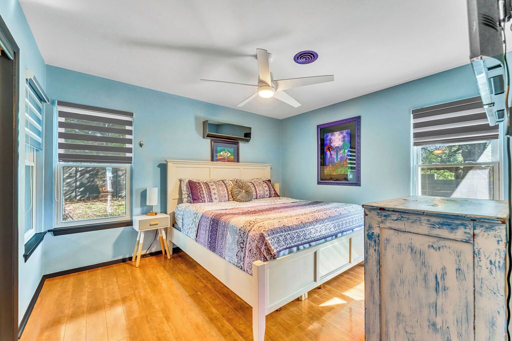 A bedroom with a bed, a ceiling fan, a nightstand, a dresser, and a window with blinds.