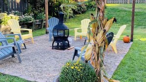 Ein Garten mit Terrasse, Gartenmöbeln, einem Blumentopf und einem Kürbis.