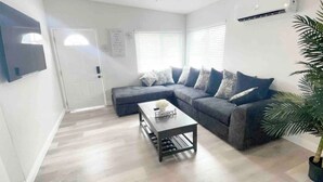 A living room with a sectional sofa, a coffee table, and a potted plant.