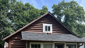 Eine Blockhütte mit Veranda, Briefkasten und Bank.