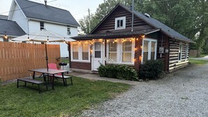 Eine Holzhütte mit Veranda, Tisch und Stühlen sowie einer Schotterauffahrt.