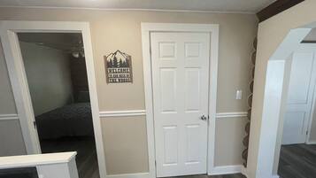 A hallway with a door, a bed, and a welcome sign.