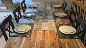 A dining table set for six with black chairs, a striped placemat, and a metal bowl centerpiece. - Restored watermill with stunning views of Loch Fyne (Kilfinan)
