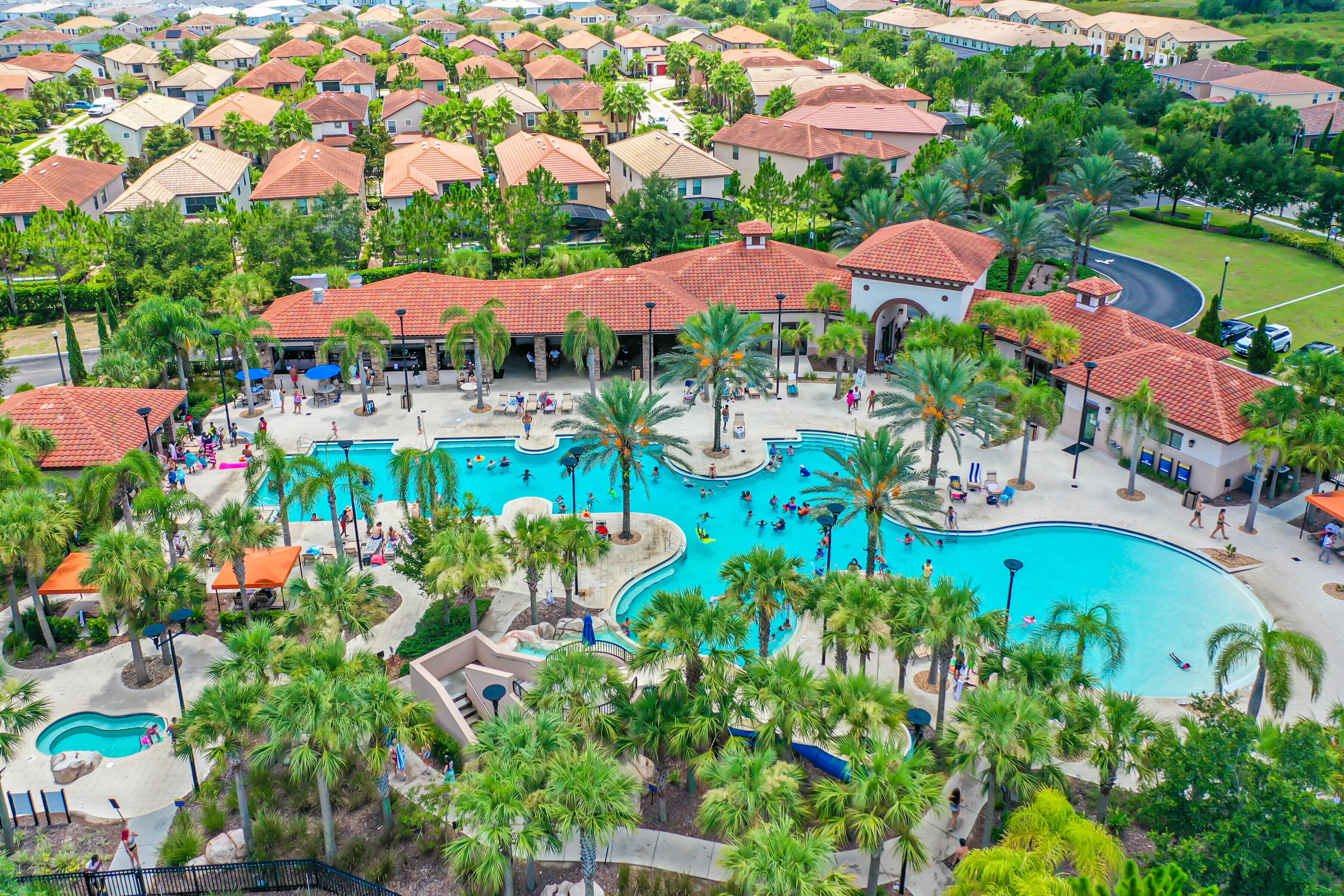 Een resort met meerdere zwembaden, palmbomen en een groot gebouw met een rood dak.