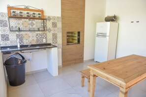 A compact kitchen with a wooden table, a built-in oven, and a refrigerator.